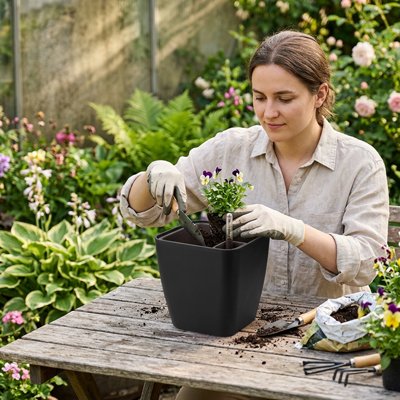 une femme plante une plante dans le Pot de fleurs