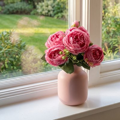 Bouquet de fleurs artificielles rose  aux rebords de fenêtre