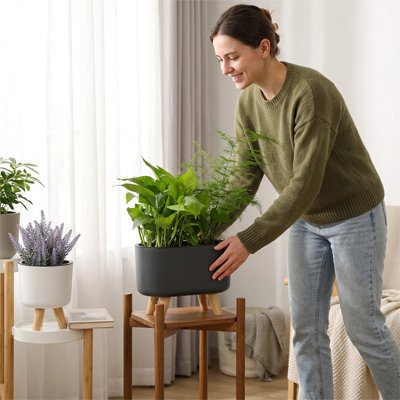 une femme met le Pot de fleurs sur une table dans le salon