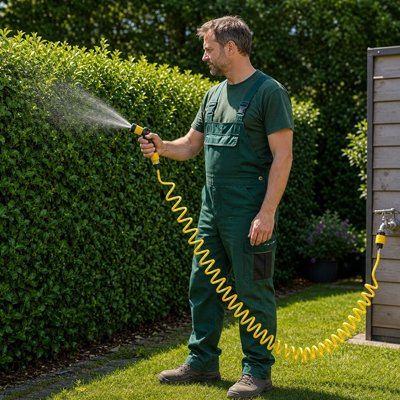Un homme qui arrose son arbuste avec le Tuyau d'arrosage spiralé
