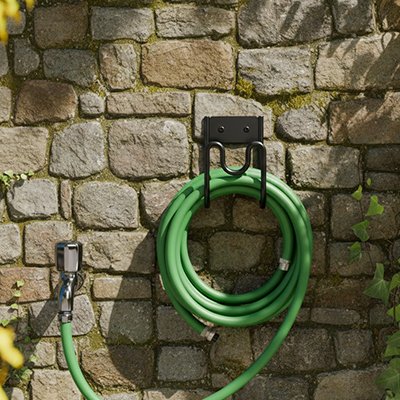 Support tuyau arrosage bien accroché sur un mur avec son tuyau 