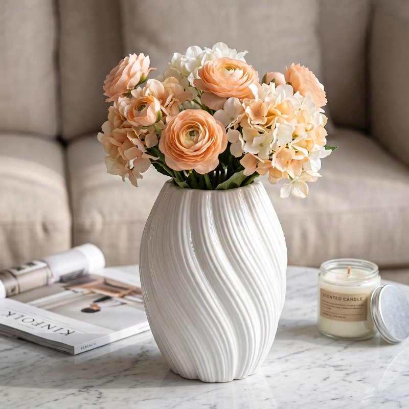 Vase blanc décoratif avec bouquet de fleurs artificielles aux couleurs pêche, crème et blanc.