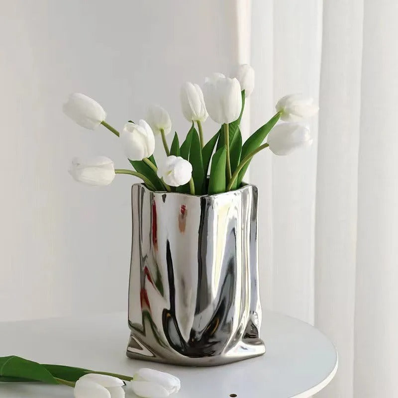 un vase fleur argent sur la table avec des tulipe blanc.