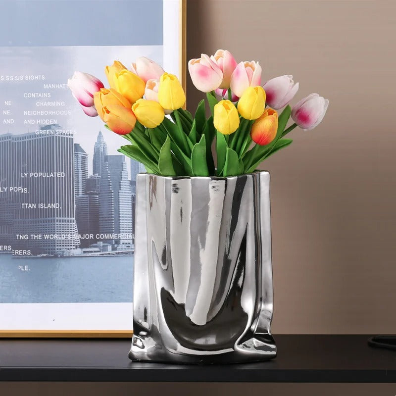 un vase fleur sur un meuble devant un tableau.