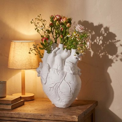 Vase en forme de cœur avec des fleur dedans sur la table de chevet 