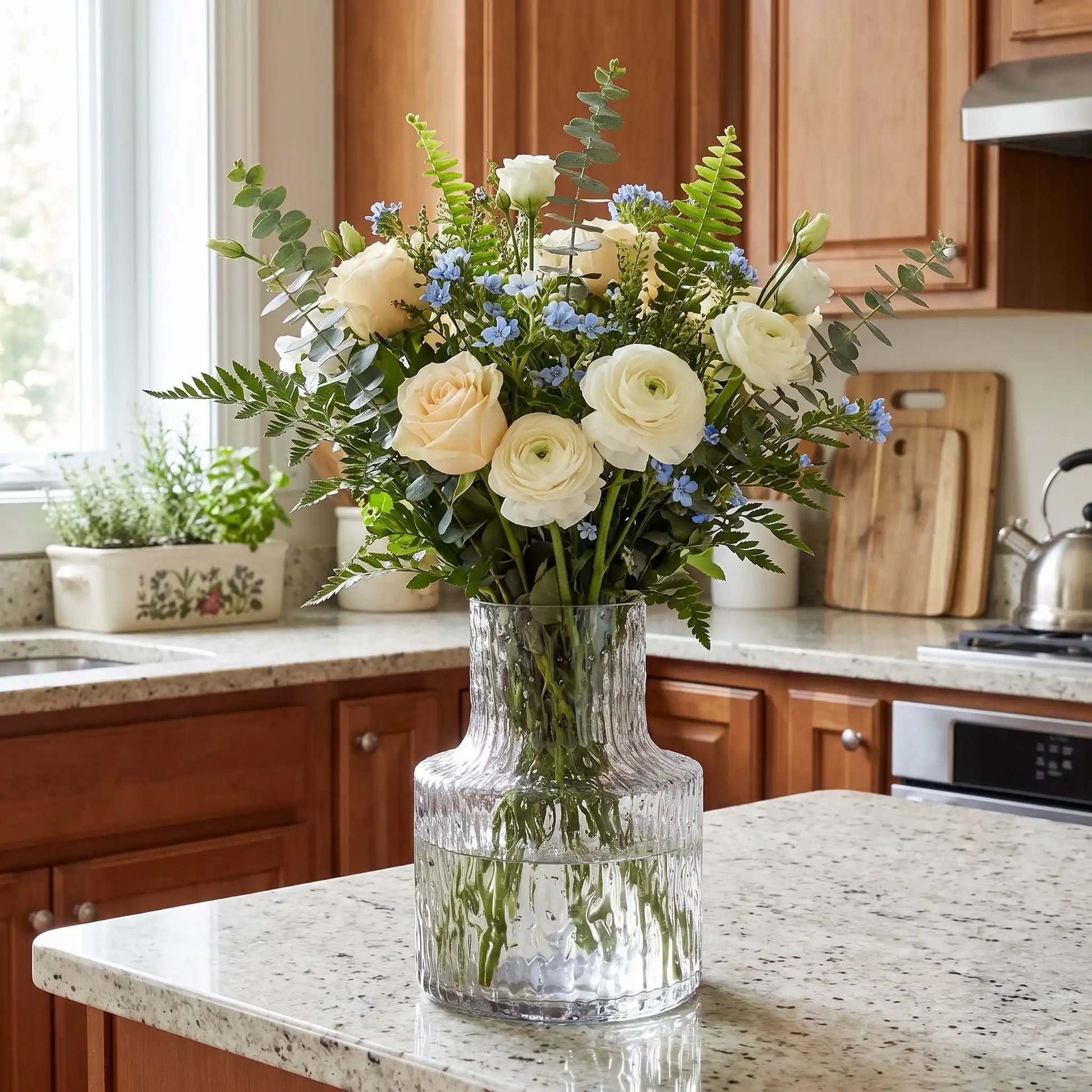 un vase en verre avec des fleurs sur le comptoir de la cuisine 
