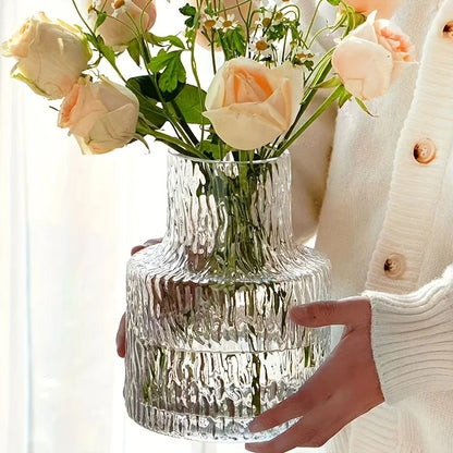 un vase en verre dans les mains d'une femme avec des fleurs